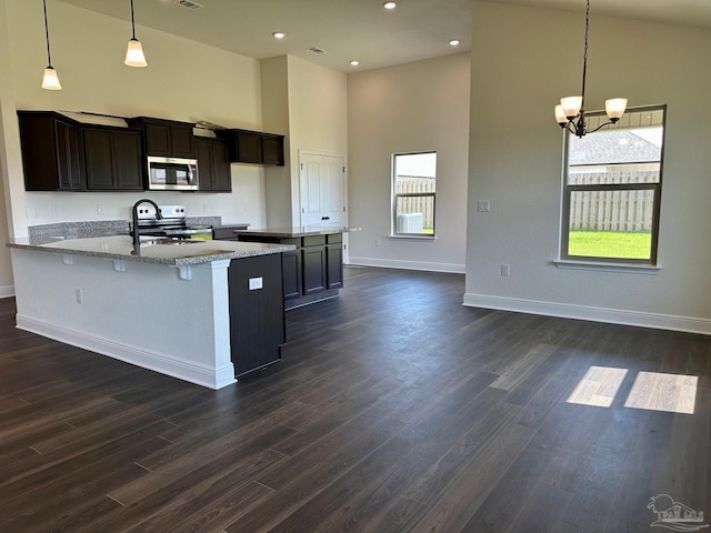 kitchen featuring stainless steel appliances, high vaulted ceiling, a notable chandelier, and baseboards