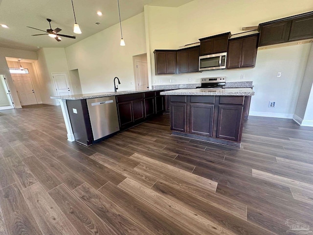 kitchen featuring a kitchen island with sink, dark wood-style floors, high vaulted ceiling, and stainless steel appliances