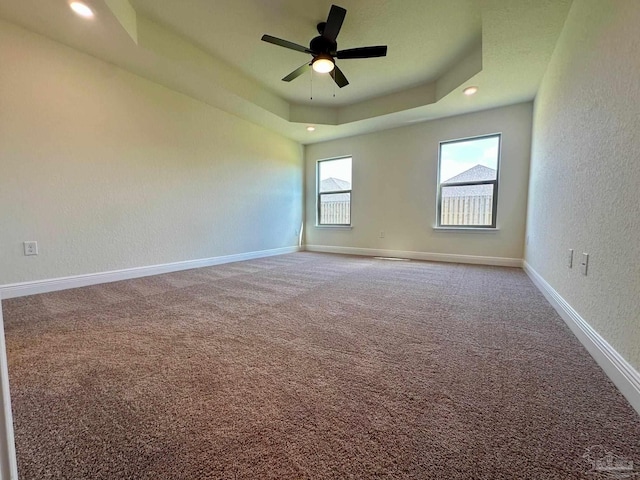carpeted empty room featuring baseboards, a textured wall, ceiling fan, and a tray ceiling