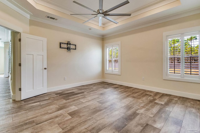 unfurnished room featuring a healthy amount of sunlight, a raised ceiling, and crown molding