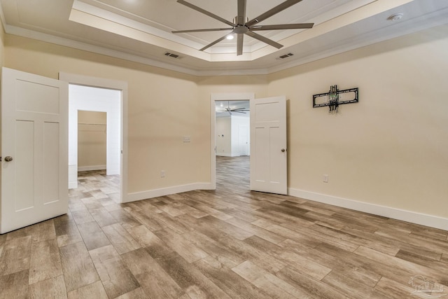 spare room with ceiling fan, light hardwood / wood-style floors, a raised ceiling, and crown molding