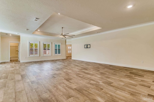 unfurnished living room featuring crown molding, light hardwood / wood-style flooring, ceiling fan, a textured ceiling, and a tray ceiling