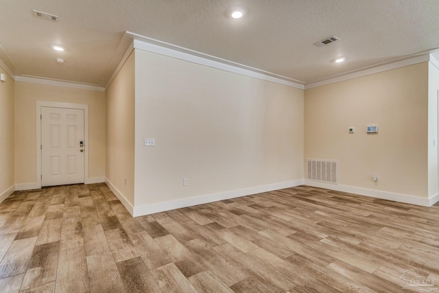 unfurnished room with a textured ceiling, light wood-type flooring, and ornamental molding