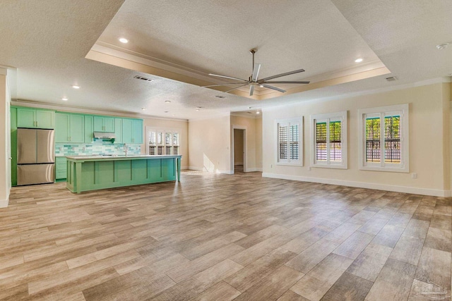 unfurnished living room with light wood-type flooring, a textured ceiling, and a tray ceiling