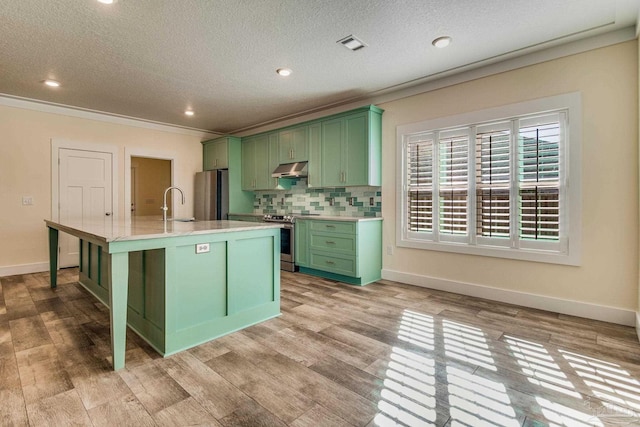 kitchen with green cabinets, light wood-type flooring, an island with sink, and appliances with stainless steel finishes