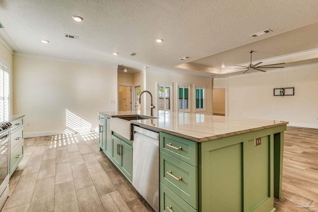 kitchen with a center island with sink, sink, green cabinetry, light hardwood / wood-style floors, and stainless steel appliances