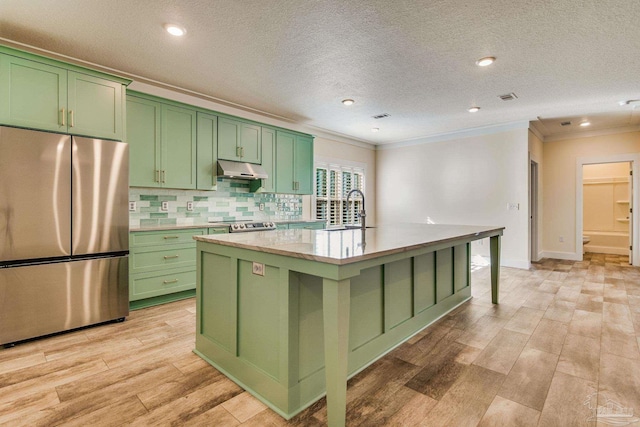 kitchen with sink, a center island with sink, stainless steel appliances, and green cabinetry