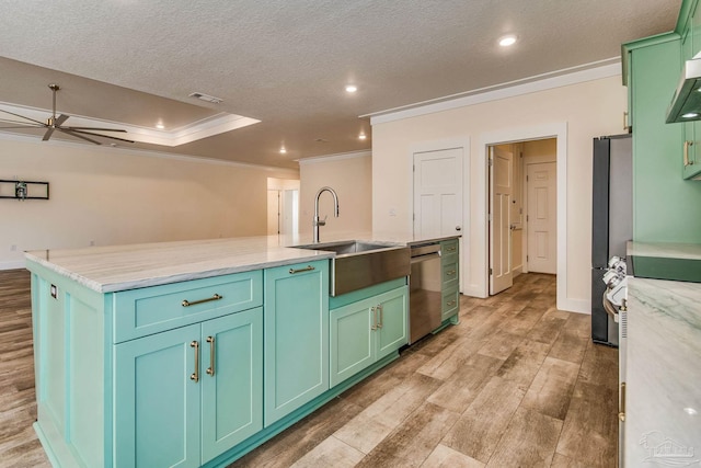 kitchen featuring ceiling fan, sink, light hardwood / wood-style flooring, green cabinets, and an island with sink