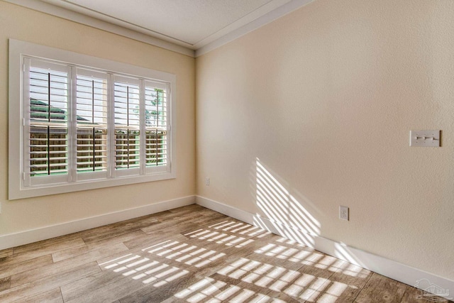 spare room with crown molding and light hardwood / wood-style flooring