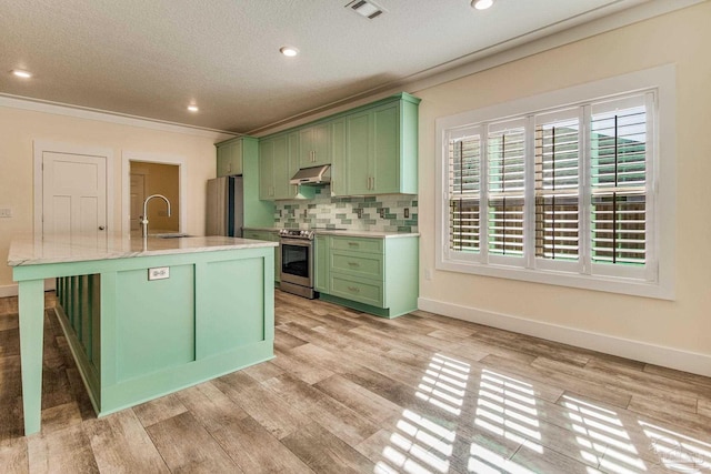 kitchen featuring a center island with sink, green cabinets, sink, light wood-type flooring, and appliances with stainless steel finishes