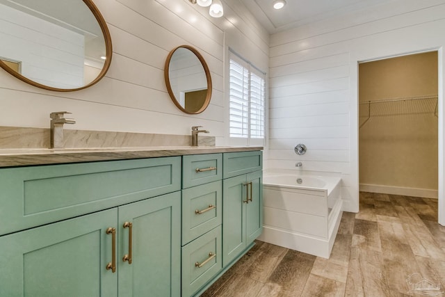 bathroom with wood walls, a washtub, vanity, and hardwood / wood-style flooring