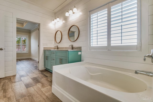 bathroom featuring a bathtub, vanity, wood-type flooring, and ornamental molding