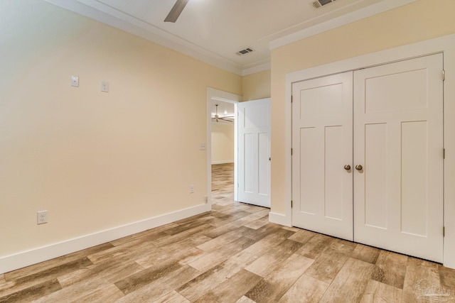 unfurnished bedroom featuring a closet, light hardwood / wood-style flooring, ceiling fan, and crown molding