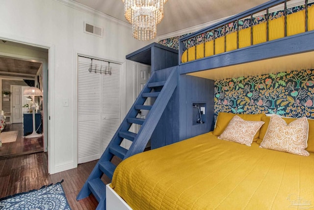 bedroom featuring hardwood / wood-style floors, a high ceiling, a closet, an inviting chandelier, and crown molding