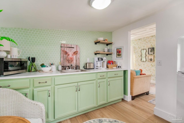 kitchen featuring light wood-type flooring, sink, white refrigerator, and green cabinets