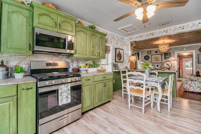 kitchen featuring backsplash, appliances with stainless steel finishes, light hardwood / wood-style floors, ceiling fan, and green cabinetry