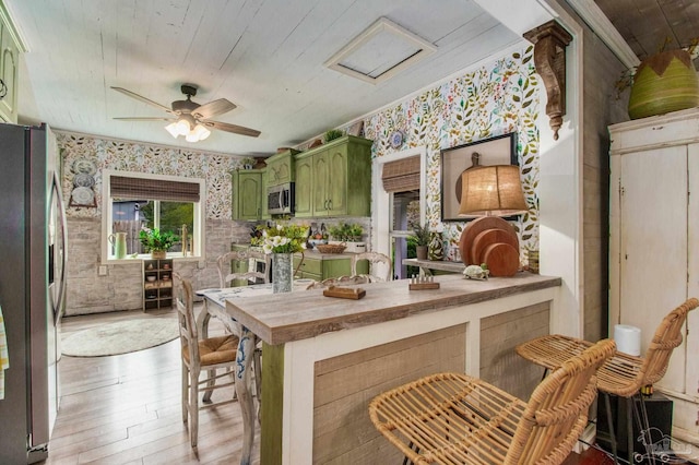 kitchen with ceiling fan, green cabinets, appliances with stainless steel finishes, and light wood-type flooring