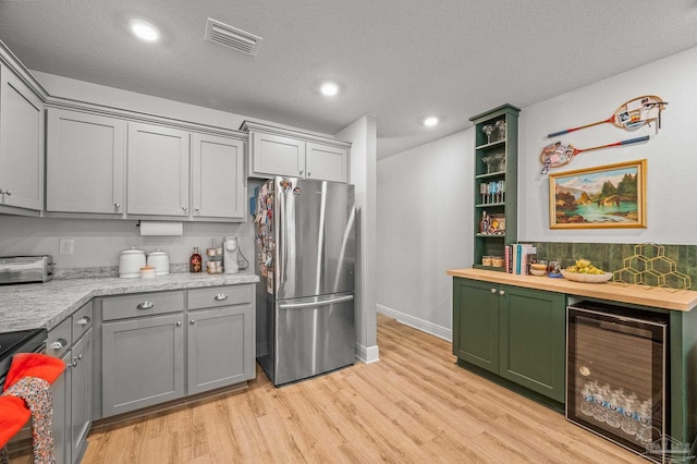 8820 Smiley Ct, Pensacola, FL 32514 - kitchen with freestanding refrigerator, wine cooler, light wood-style floors, gray cabinets, and stove