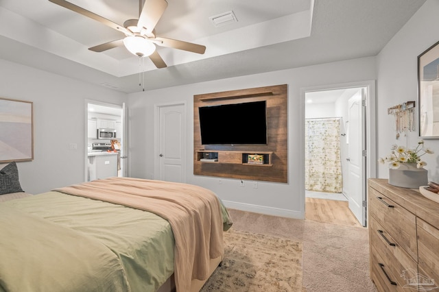 8820 Smiley Ct, Pensacola, FL 32514 - bedroom with a tray ceiling, light carpet, connected bathroom, and ceiling fan
