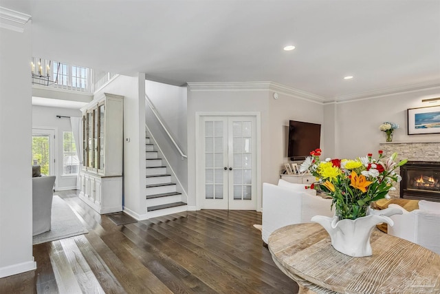 foyer entrance with a fireplace, ornamental molding, dark wood-type flooring, and french doors