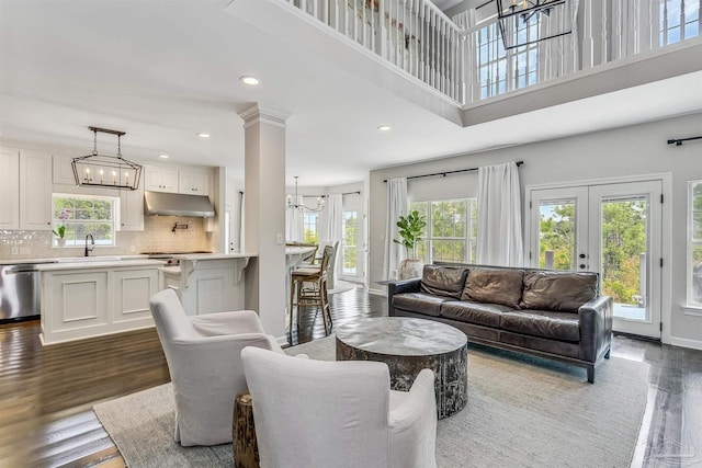 living room featuring french doors, dark hardwood / wood-style flooring, ornate columns, sink, and a high ceiling