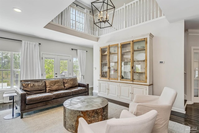 living room with hardwood / wood-style flooring, a healthy amount of sunlight, a high ceiling, and french doors