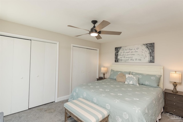 bedroom with ceiling fan, light carpet, and multiple closets