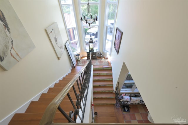 stairway featuring a notable chandelier and wood finished floors