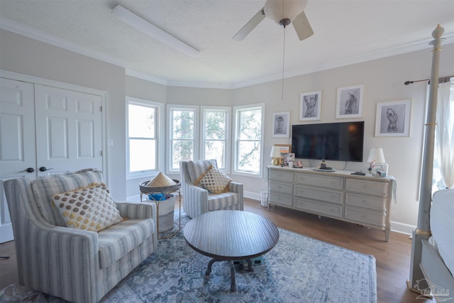 living area with ornamental molding, dark wood finished floors, baseboards, and ceiling fan