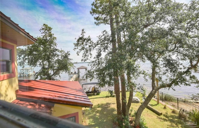 view of property's community featuring a lawn, a water view, and fence