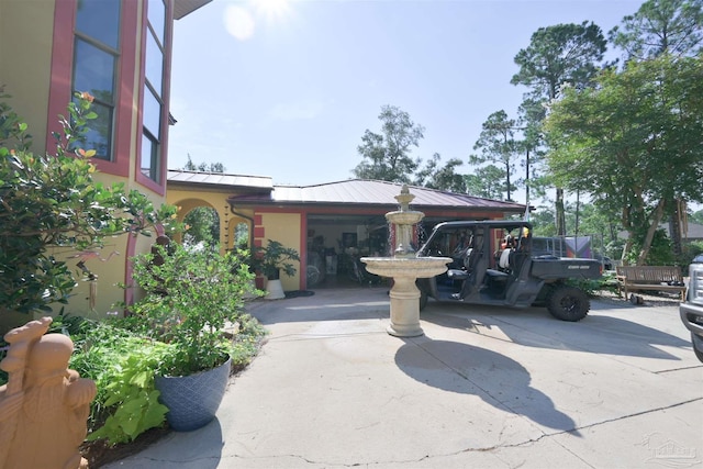 exterior space featuring metal roof, driveway, a standing seam roof, and stucco siding