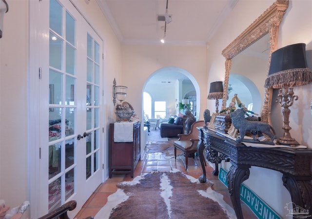 hall featuring arched walkways, light tile patterned flooring, crown molding, and rail lighting