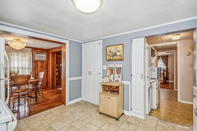 kitchen featuring an AC wall unit, crown molding, light hardwood / wood-style flooring, a textured ceiling, and a chandelier