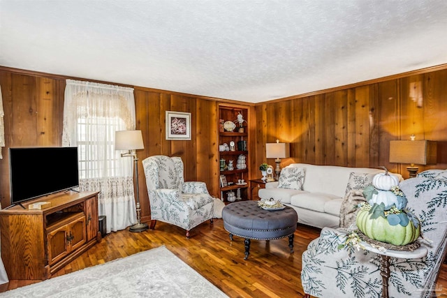 living room featuring dark hardwood / wood-style flooring, ornamental molding, a textured ceiling, and wooden walls