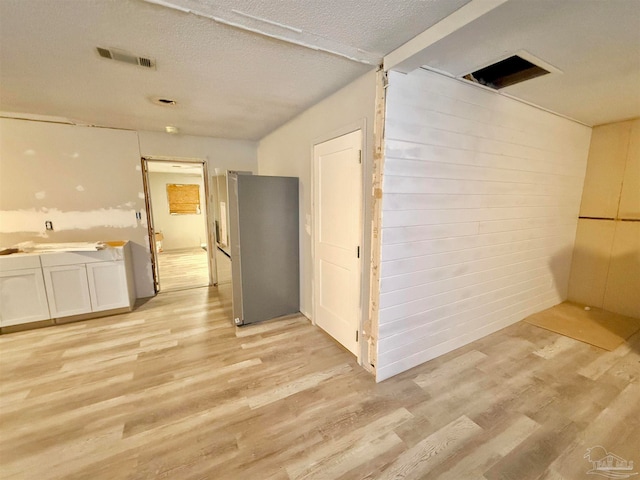 corridor featuring a textured ceiling and light hardwood / wood-style flooring