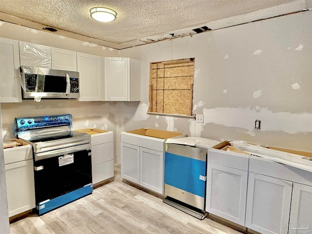 kitchen with light hardwood / wood-style flooring, white cabinets, a textured ceiling, and black / electric stove