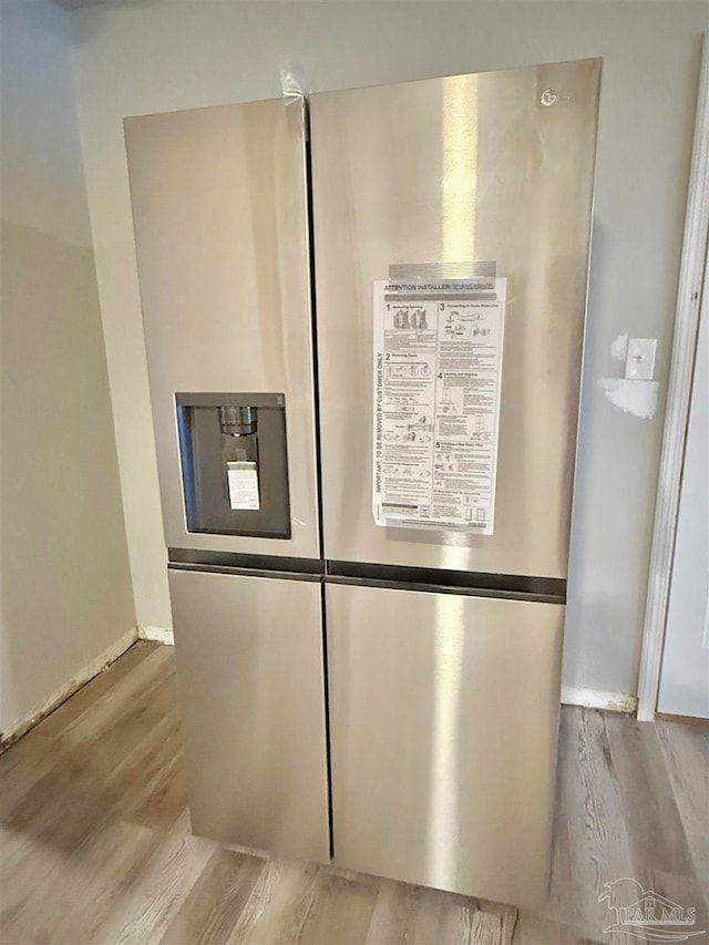 room details featuring light wood-type flooring and stainless steel fridge with ice dispenser