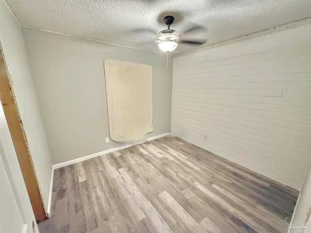 unfurnished room with ceiling fan, a textured ceiling, and light hardwood / wood-style flooring