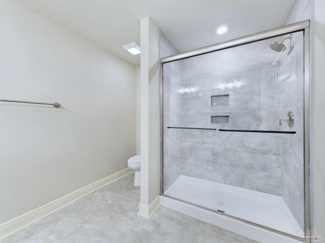 bathroom with a stall shower, toilet, and baseboards