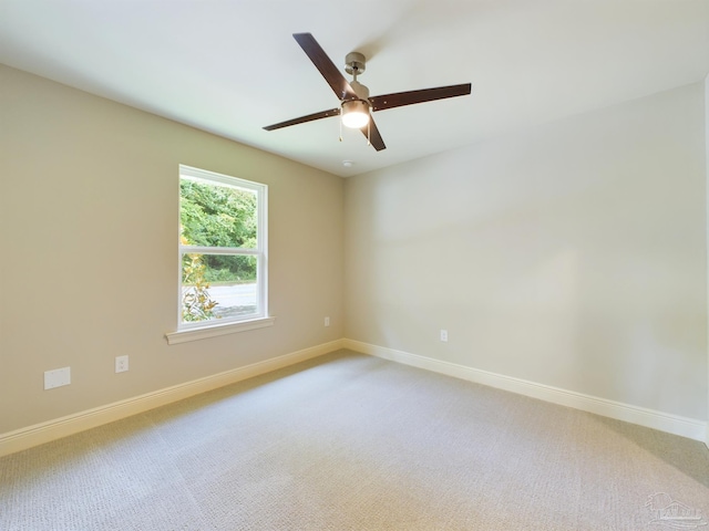 carpeted spare room with ceiling fan and baseboards