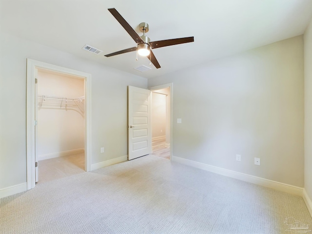 unfurnished bedroom featuring light colored carpet, visible vents, baseboards, a spacious closet, and a closet