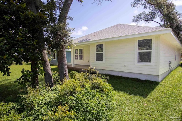 back of house featuring a yard and roof with shingles