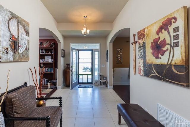 entrance foyer featuring arched walkways, light tile patterned flooring, visible vents, and baseboards