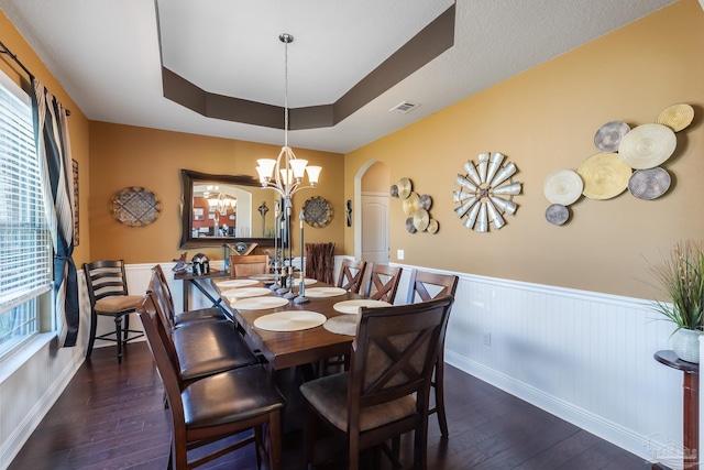 dining room with visible vents, arched walkways, a wainscoted wall, dark wood-style flooring, and a tray ceiling