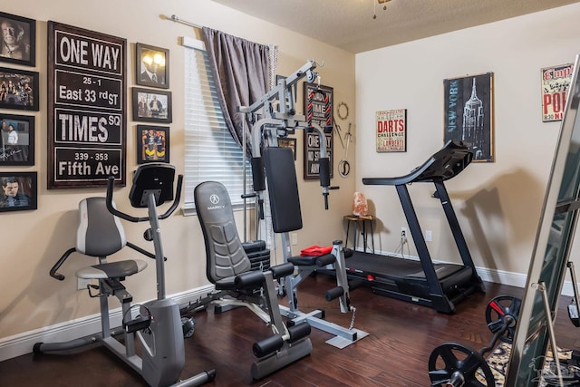 exercise room with dark wood finished floors and baseboards