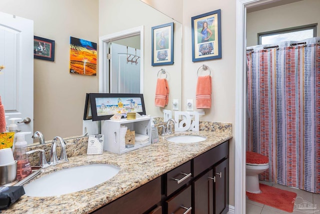 full bath featuring toilet, tile patterned flooring, double vanity, and a sink