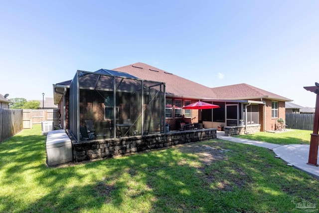 rear view of property featuring a yard, a lanai, a patio area, and brick siding