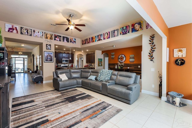 living area featuring visible vents, arched walkways, baseboards, ceiling fan, and light tile patterned flooring