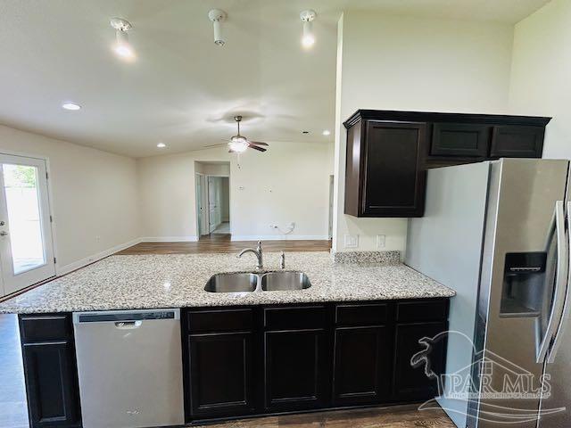 5643 Flume Dr, Pace, FL 32571 - kitchen featuring appliances with stainless steel finishes, a sink, dark cabinetry, open floor plan, and light stone countertops