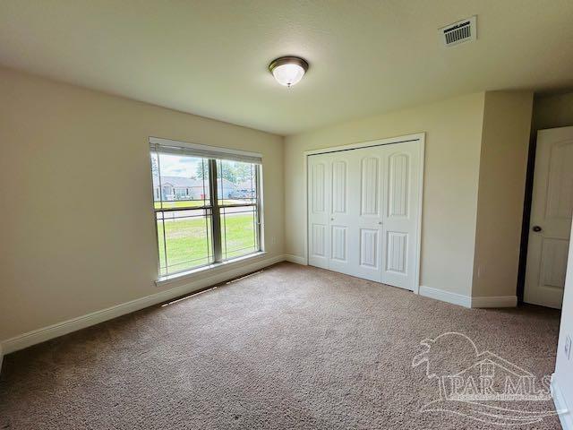 5643 Flume Dr, Pace, FL 32571 - unfurnished bedroom with baseboards, carpet flooring, and a closet